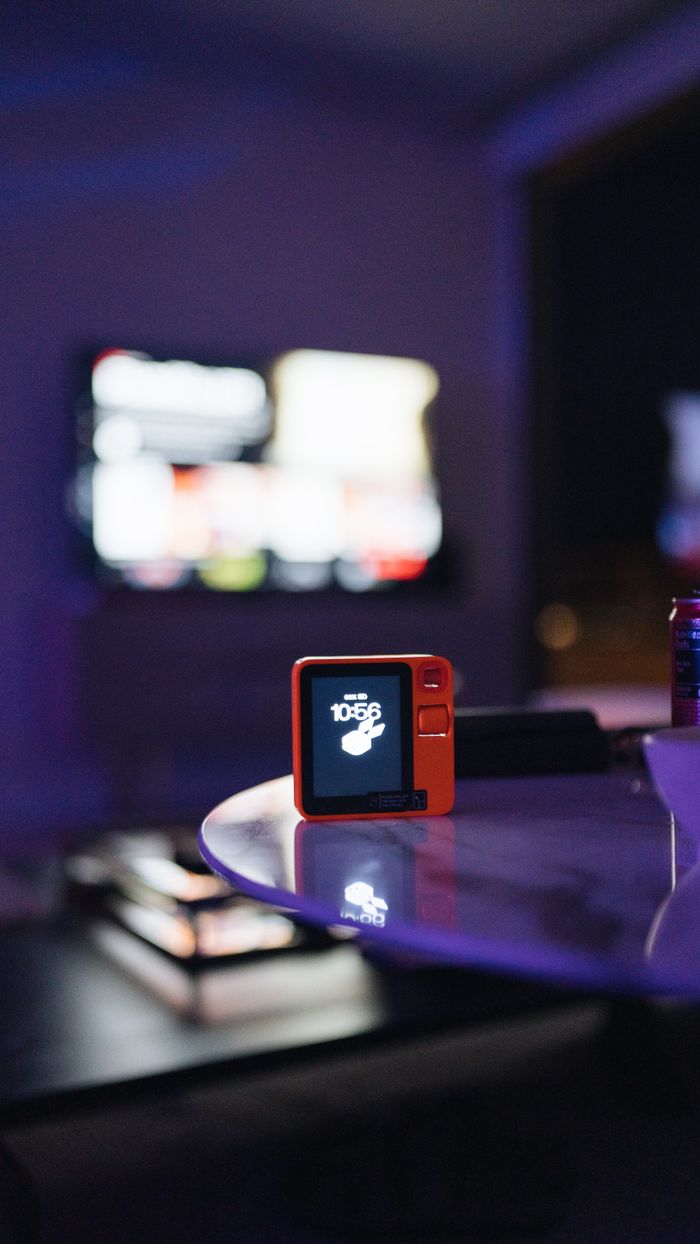 A digital device on a glass table in a neon-lit modern indoor setting.